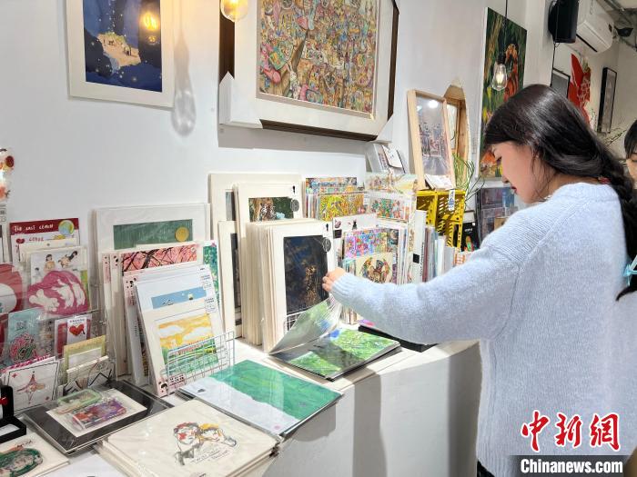 圖為藝術(shù)品商店內(nèi)，顧客挑選插畫作品。　鐘旖 攝