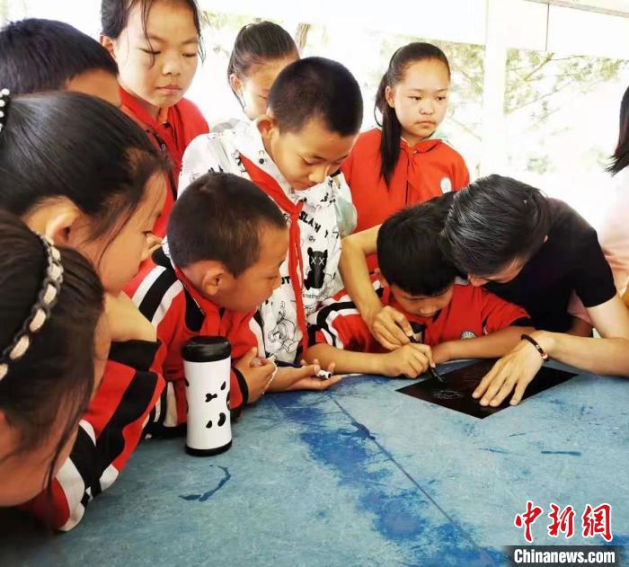 圖為朱增平(右一)教學(xué)生創(chuàng)作鍥金畫(huà)。(資料圖) 受訪者供圖