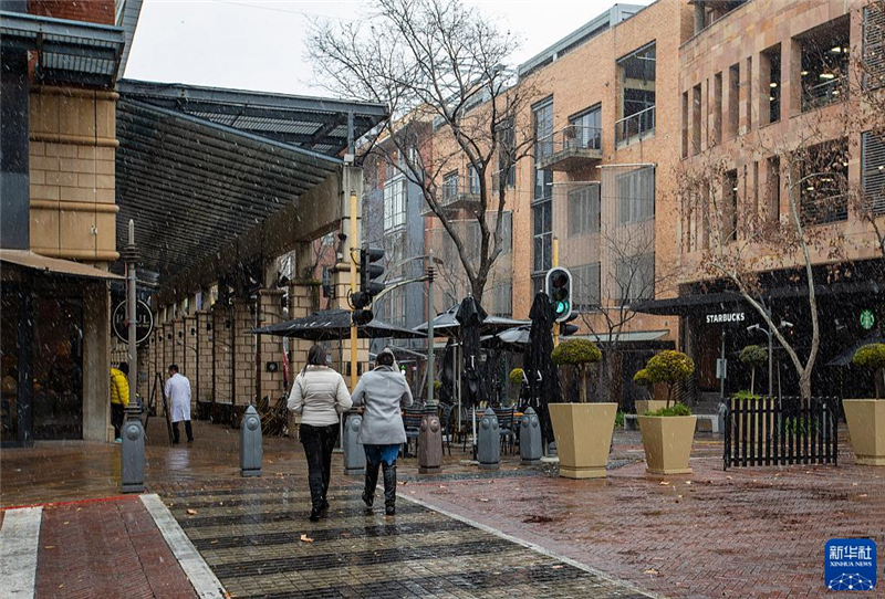 7月10日，在南非約翰內(nèi)斯堡一處商業(yè)區(qū)，人們?cè)谘┲行凶?。新華社記者 張譽(yù)東 攝