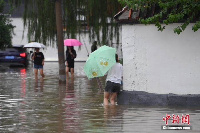 7月31日，市民行走在雨中的北京房山區(qū)瓦窯頭村。北京市氣象臺(tái)當(dāng)日10時(shí)發(fā)布分區(qū)域暴雨紅色預(yù)警信號(hào)。北京市水文總站發(fā)布洪水紅色預(yù)警，預(yù)計(jì)當(dāng)日12時(shí)至14時(shí)，房山區(qū)大石河流域?qū)⒊霈F(xiàn)紅色預(yù)警標(biāo)準(zhǔn)洪水。<a target='_blank' href='/'><p  align=