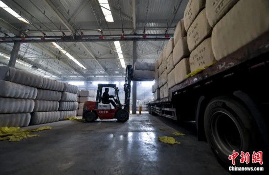 新疆喀什綜合保稅區(qū)，喀什啟路國際貿(mào)易有限公司的倉庫內(nèi)，工人正在裝載從塔吉克斯坦和烏茲別克斯坦進口的棉花。劉新攝