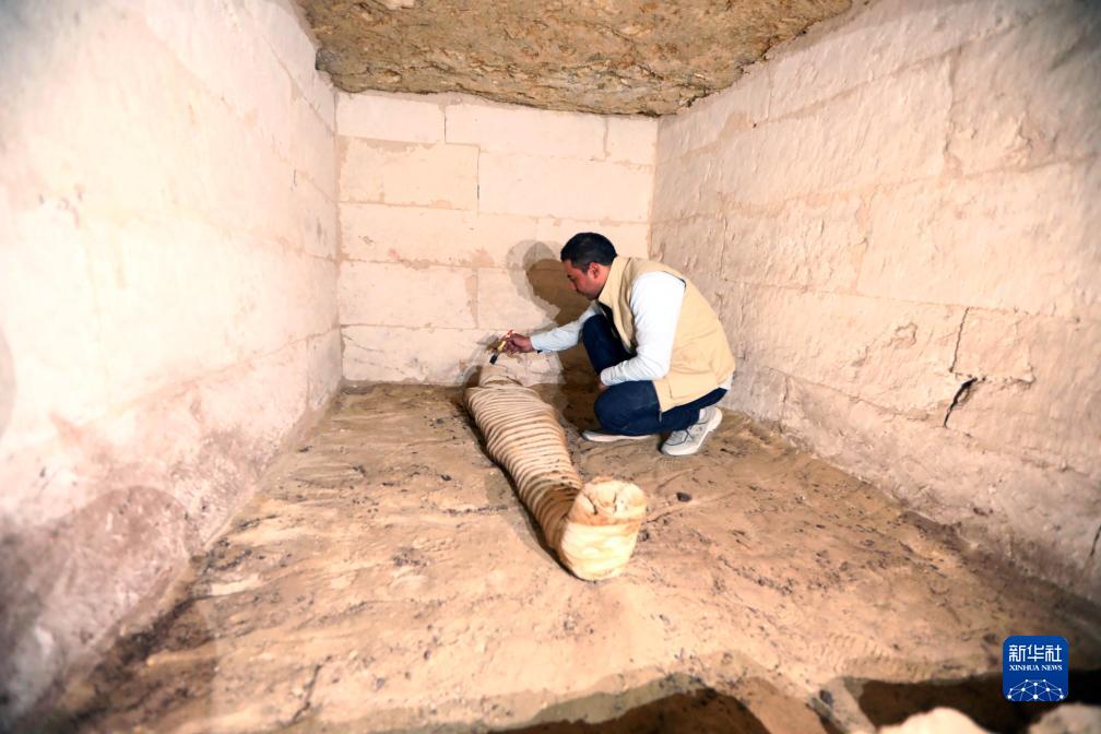 10月15日，在埃及明亞省考古現(xiàn)場，考古人員清理一座石鑿墓中的木乃伊。新華社發(fā)（艾哈邁德·戈馬攝）