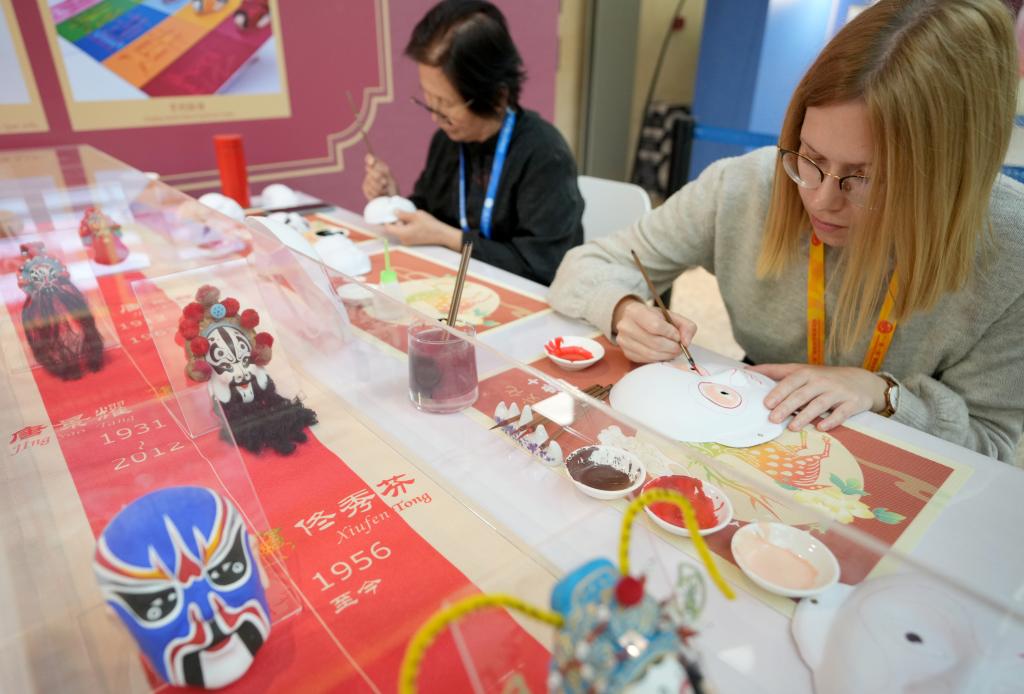 10月16日，在第三屆“一帶一路”國際合作高峰論壇新聞中心，來自比利時的記者（右）體驗畫京劇臉譜。新華社記者 王毓國 攝