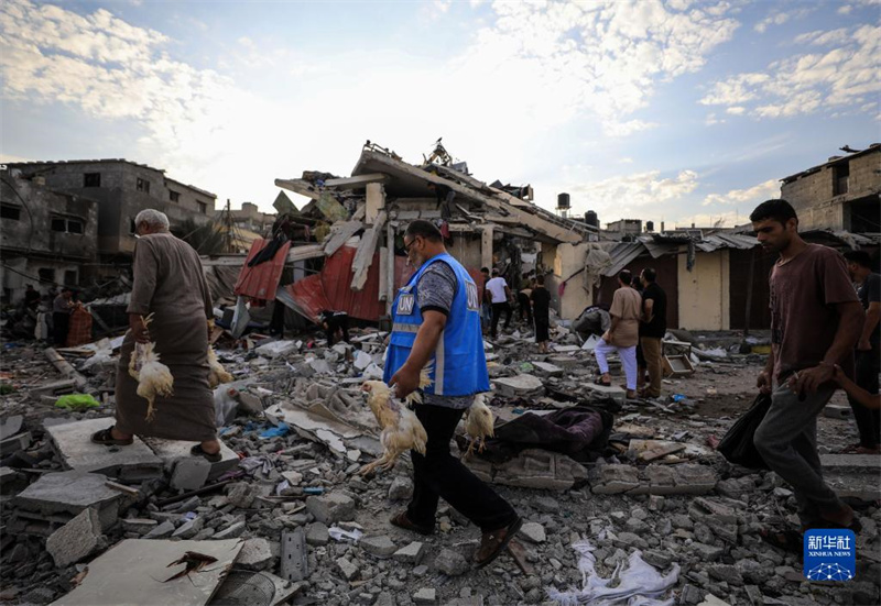 10月27日，在加沙地帶南部城市汗尤尼斯，人們經(jīng)過以軍襲擊后的房屋廢墟。