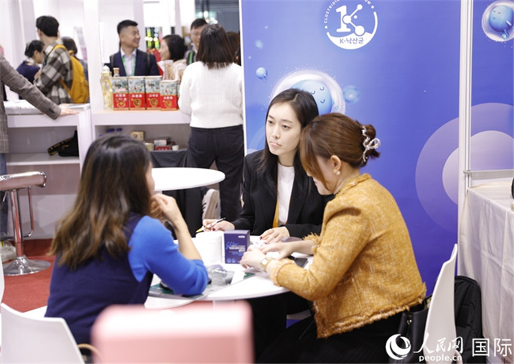 圖2:金相俊同事在展臺(tái)同客商洽談 人民網(wǎng)記者 李美玉攝