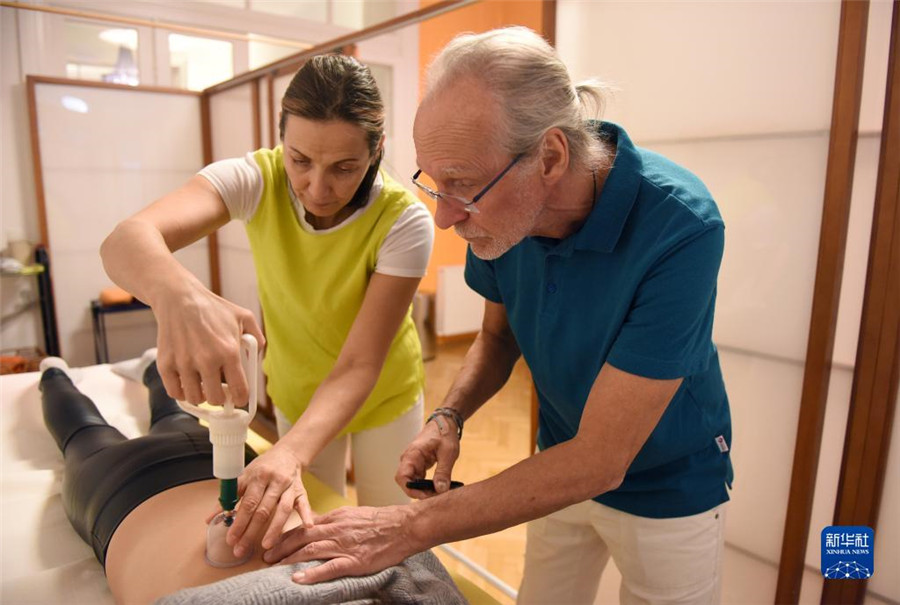 12月12日，在奧地利維也納，科格勒醫(yī)生（右）和助手在為病人進行拔罐治療。新華社記者 賀燦鈴 攝