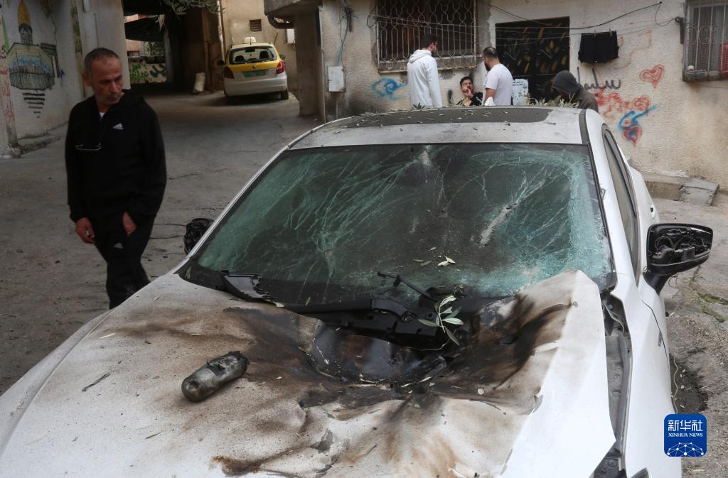 12月17日，在約旦河西岸城市圖勒凱爾姆附近的一處難民營，人們查看在沖突中損毀的車輛。新華社發(fā)（尼達(dá)爾·艾仕塔耶?dāng)z）