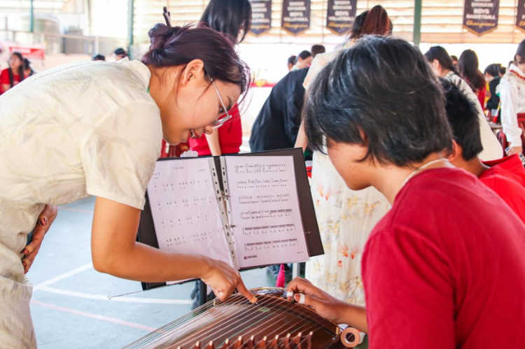 志愿者教師指導學生彈奏古箏?；顒又鬓k方供圖