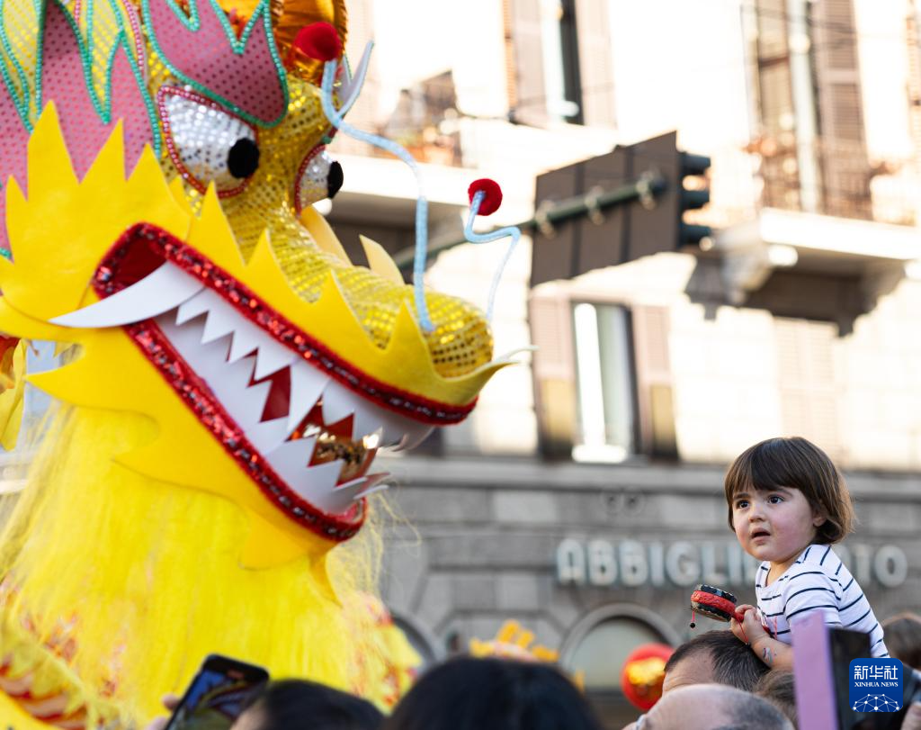 2月18日，在意大利羅馬，一名小朋友在彩妝巡游上觀看舞龍。新華社記者 李京 攝
