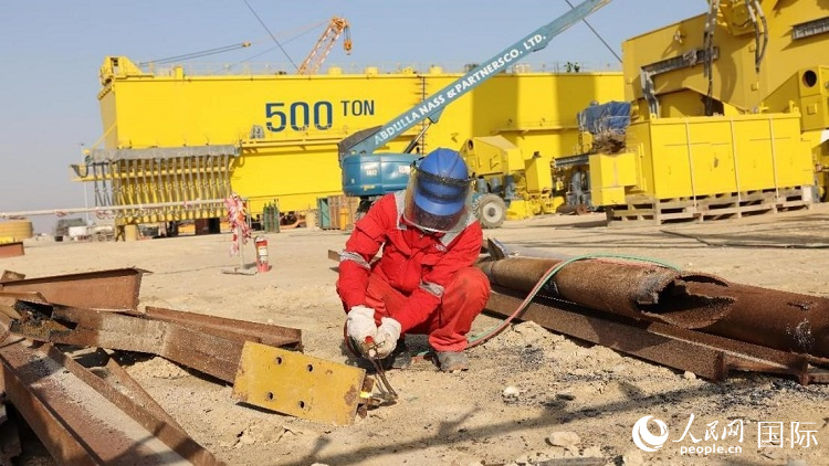 工人正在龍門吊吊裝現(xiàn)場切割金屬件。人民網(wǎng)記者管克江攝