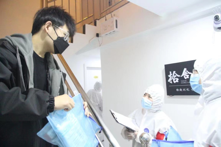 社區(qū)工作人員和志愿者身穿防護(hù)服上門送馬應(yīng)龍大健康防疫包。徐帥攝