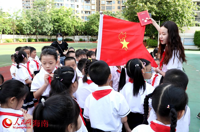 老師向少先隊(duì)員展示隊(duì)旗。人民網(wǎng) 符武平攝