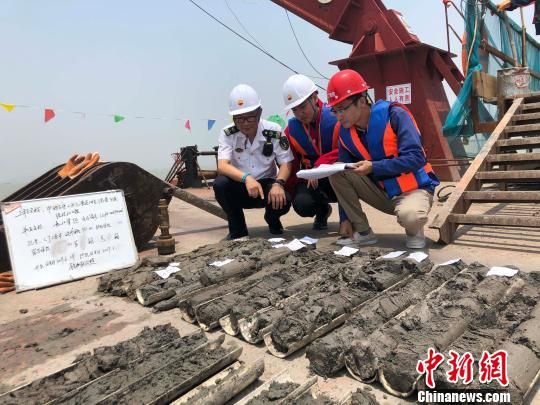 圖為勘察設(shè)計人員與海事局工作人員查看巖芯情況?！∥赫?攝