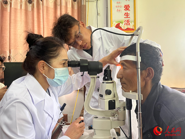 王紅英（左）和團隊成員為達熱村村民檢查眼睛。人民網(wǎng)記者 杜燕飛攝