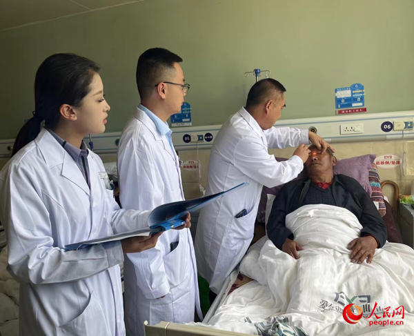 董光明（左三）帶領(lǐng)醫(yī)生對患者進行術(shù)前檢查。人民網(wǎng)記者 杜燕飛攝