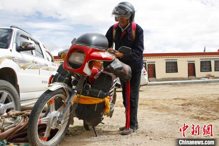 圖為白瑪準(zhǔn)備騎摩托車巡湖?！≮w朗 攝