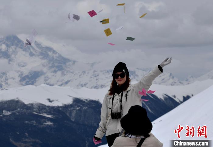 圖為5月14日，游客在西藏林芝色季拉山觀景臺拋灑“隆達(dá)”(風(fēng)馬旗，藏族民眾的一種祈福方式)?！±盍?攝