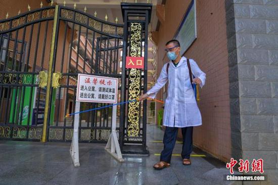 資料圖：?？诮?jīng)濟(jì)學(xué)院的工作人員在學(xué)生宿舍樓入口消毒。 中新社記者 駱云飛 攝