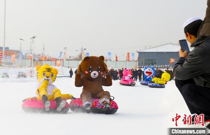 圖為臨夏市南龍鎮(zhèn)馬家莊村舉辦的鄉(xiāng)村文化旅游節(jié)上，游客穿著卡通服裝在體驗(yàn)雪上飛碟項(xiàng)目。近年來，臨夏州形成了“春賞花、夏避暑、秋摘果、冬玩雪”的全季節(jié)旅游產(chǎn)品體系。(資料圖) 高展 攝