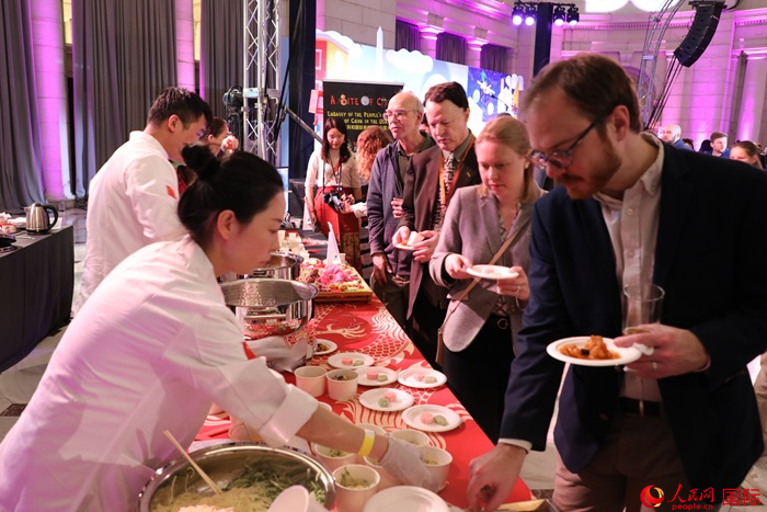 當地時間3月7日晚，華盛頓聯合車站廣場舉行駐美使團“使館主廚挑戰(zhàn)賽”。圖為當地民眾在中國展臺前體驗中國美食。人民網記者 李志偉攝