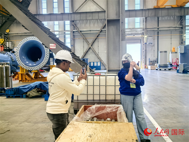 外媒記者掂量廠房內(nèi)的巨型螺栓。人民網(wǎng) 楊春燕攝