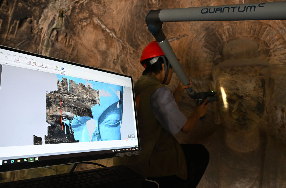 2025年4月9日，武漢大學文化遺產(chǎn)智能計算實驗室團隊成員在魏字洞使用關(guān)節(jié)臂掃描儀對佛像進行數(shù)字化掃描。圖片來源新華社