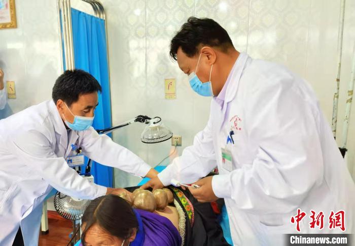 圖為看照加手把手帶徒弟加老(左一)進(jìn)行拔罐療法?！堟?攝