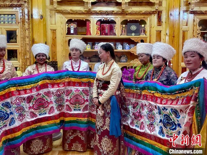 圖為女性展示村民自發(fā)繡制的“百米五彩哈達”?！±钣穹?攝