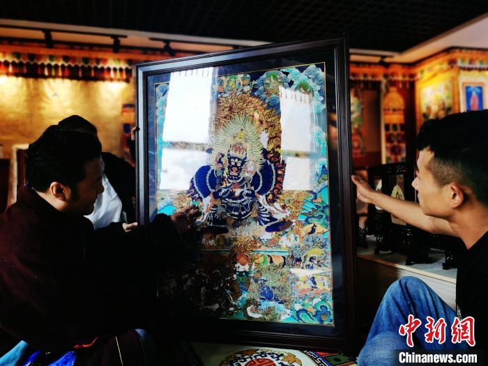 圖為久美尖措(左)與徒弟們展示唐卡作品?！?zhí)砀?攝