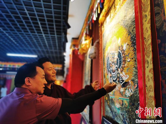 圖為久美尖措展示唐卡作品?！?zhí)砀?攝