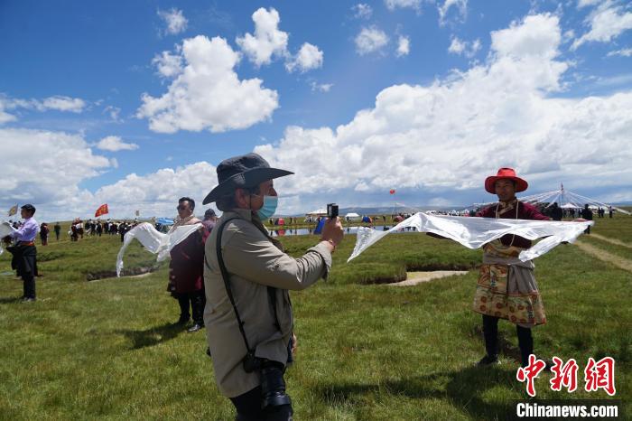 圖為一名外籍?dāng)z影師記錄當(dāng)?shù)夭刈鍤g迎儀式?！●R銘言 攝