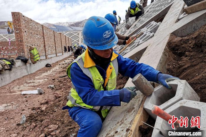 圖為光伏發(fā)電項目施工區(qū)工人在護坡鋪設(shè)空心磚?！±铍h 攝