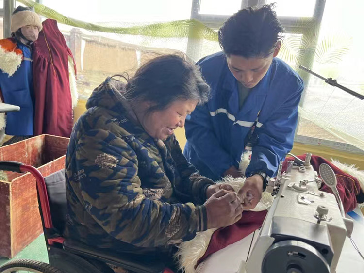 扎西奪爾登幫助殘疾員工裁剪。阿壩州文明辦供圖