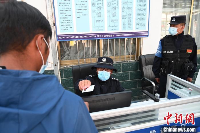 圖為移民管理警察登記完身份信息后將證件歸還給行人?！≮w朗 攝