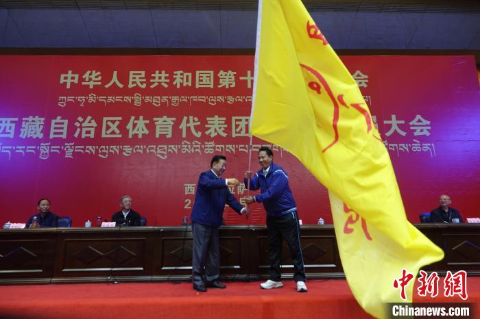 西藏自治區(qū)副主席甲熱·洛桑丹增授代表團團旗，西藏自治區(qū)體育局局長尼瑪次仁接旗?！∪轿木?攝