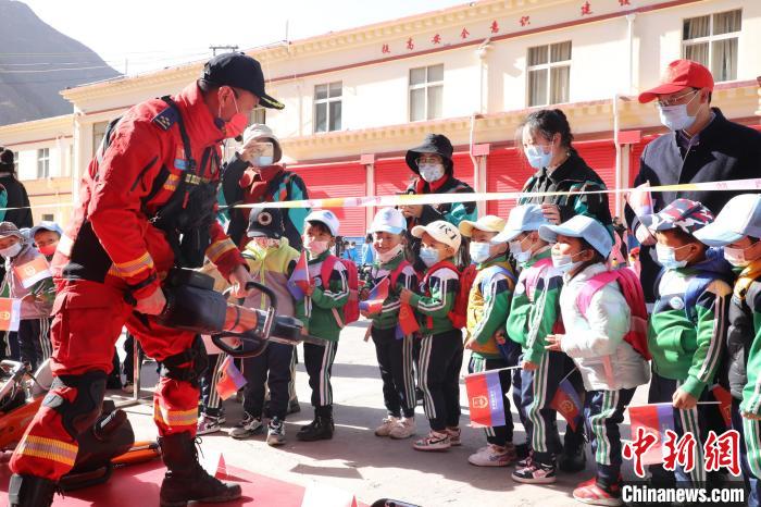 圖為消防指戰(zhàn)員為學(xué)生講解、演示先進救援裝備?！≮w琳 攝