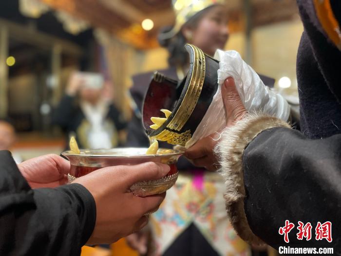 圖為主人在碗中斟滿青稞酒?！∪轿木?攝