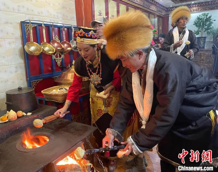 圖為人們在火上烤節(jié)日美食“結(jié)達(dá)”?！∪轿木?攝