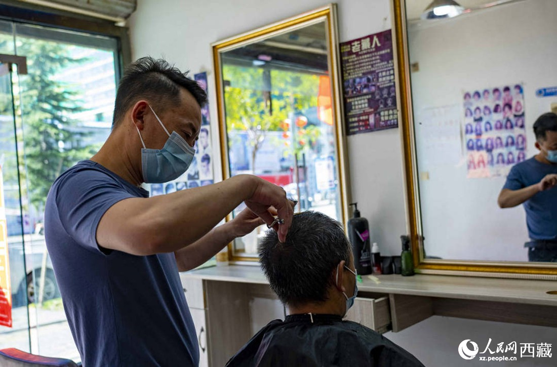 理發(fā)店老板為顧客理發(fā)。次仁羅布 攝
