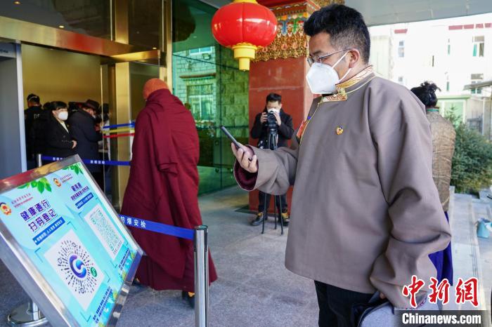 圖為政協(xié)委員掃場所碼進入會場?！〗w波 攝