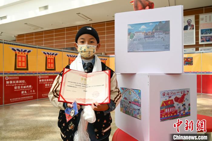 圖為一名獲獎(jiǎng)學(xué)生與自己的繪畫作品合影?！≮w朗 攝