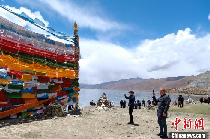 進(jìn)藏參訪嘉賓在羊湖畔拍攝經(jīng)幡。　江飛波 攝