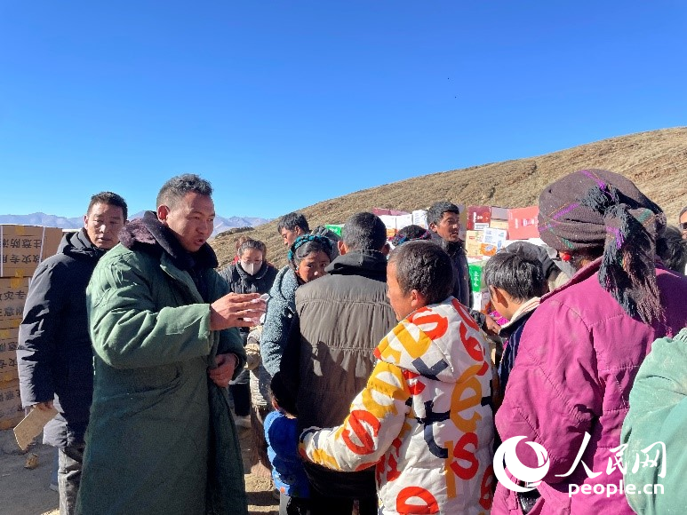 定日縣公安局干警頓珠次仁（左二）正在協(xié)助分發(fā)物資。人民網(wǎng)記者 郝潔攝